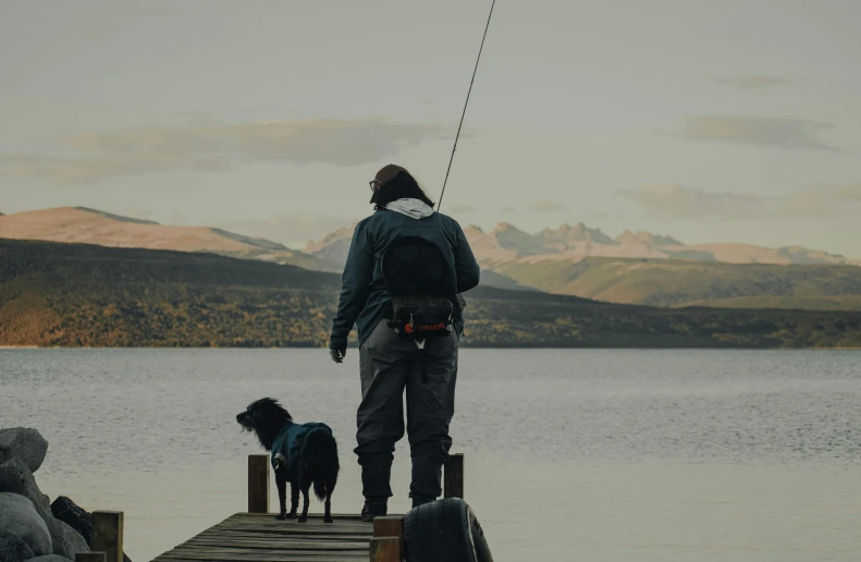 a man standing on a dock with two dogs, pexels contest winner, fishing pole, patagonian, male and female, screensaver