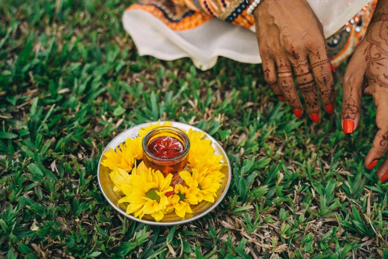 a woman sitting on top of a grass covered field, an album cover, pexels contest winner, hurufiyya, holding hot sauce, kalighat flowers, blessing hands, ethiopian
