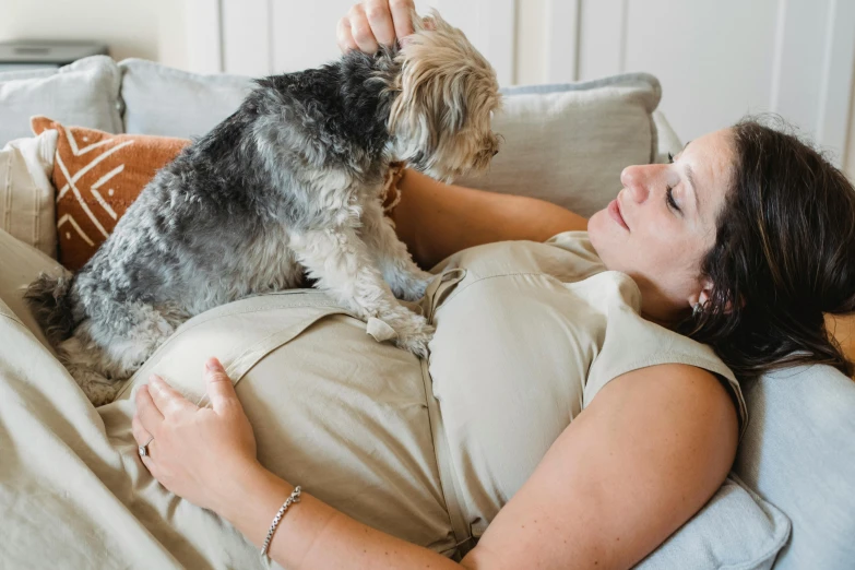 a woman laying on a couch with a dog, by Arabella Rankin, pexels contest winner, happening, pregnant belly, australian, full body shot close up, thumbnail