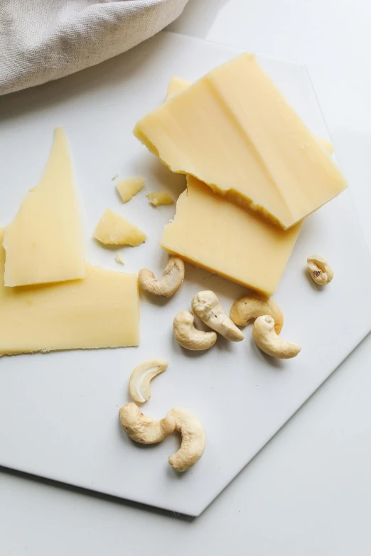 a cutting board topped with cheese and cashews, by Kristin Nelson, soft pale tone, thumbnail, good, silk