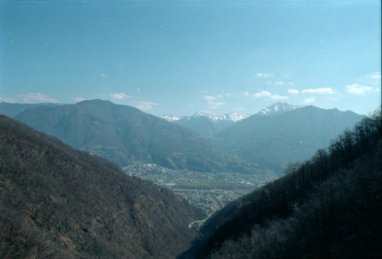 a view of a valley with mountains in the background, taken on a 2000s camera, furio tedeschi, alessio albi, entire city visible