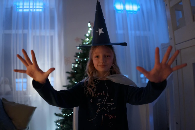 a little girl standing in front of a christmas tree, a hologram, inspired by Ida Rentoul Outhwaite, shutterstock contest winner, black witch hat and broomstick, 8k cinematic shot, t-pose of male magic wizard, indigo magician