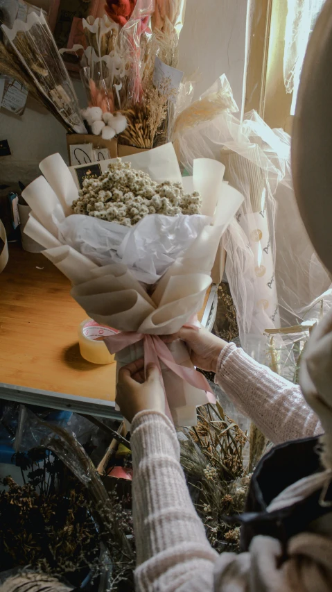 a woman holding a bunch of dried flowers, a cartoon, by Lucia Peka, pexels contest winner, white and pink cloth, made of paper, low quality photo, indonesia