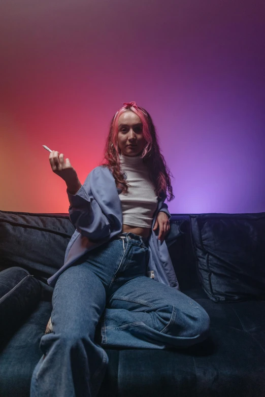 a woman sitting on top of a black couch, an album cover, inspired by Elsa Bleda, trending on pexels, giving the middle finger, colored lighting, portrait of maci holloway, bisexual lighting