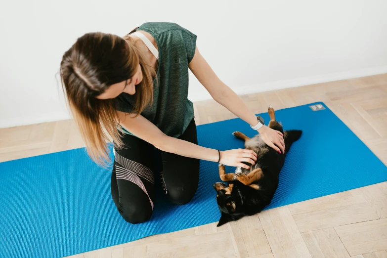 a woman sitting on a yoga mat petting a dog, by Emma Andijewska, private press, low quality photo, high quality upload, fit physique, petting a cat