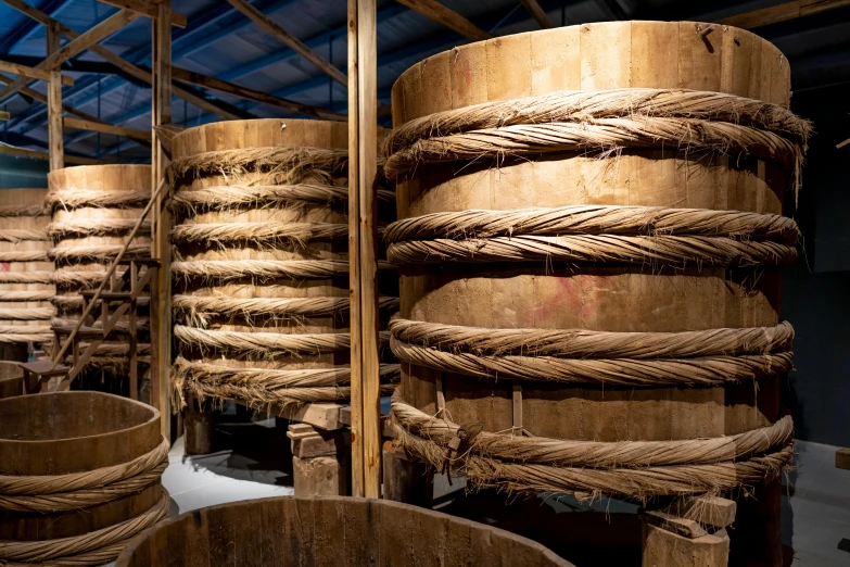 a bunch of wooden barrels stacked on top of each other, by Yasushi Sugiyama, trending on unsplash, process art, rope bridges, silk robes, cavernous interior wide shot, thumbnail