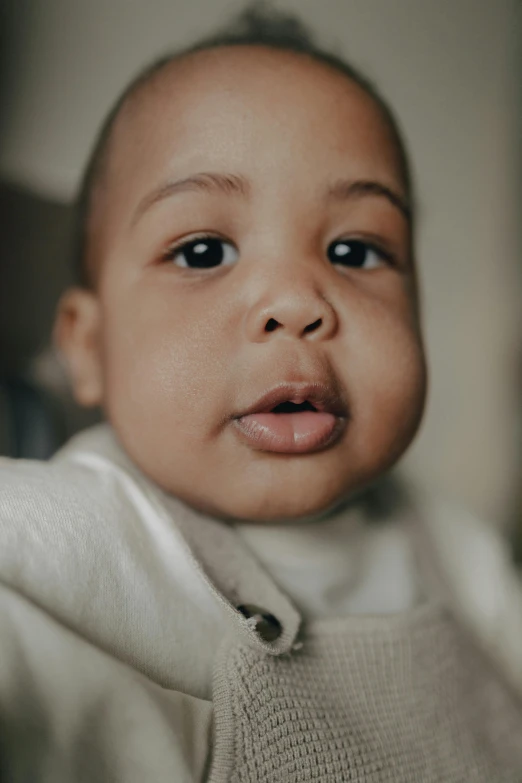 a close up of a baby wearing a sweater, unsplash, hyperrealism, big lips, light-brown skin, full frame image, a handsome