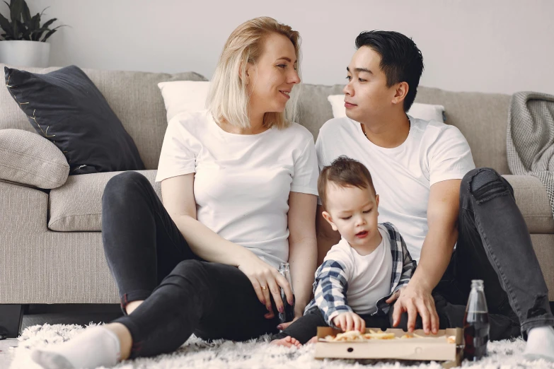 a man and woman sitting on the floor with a baby