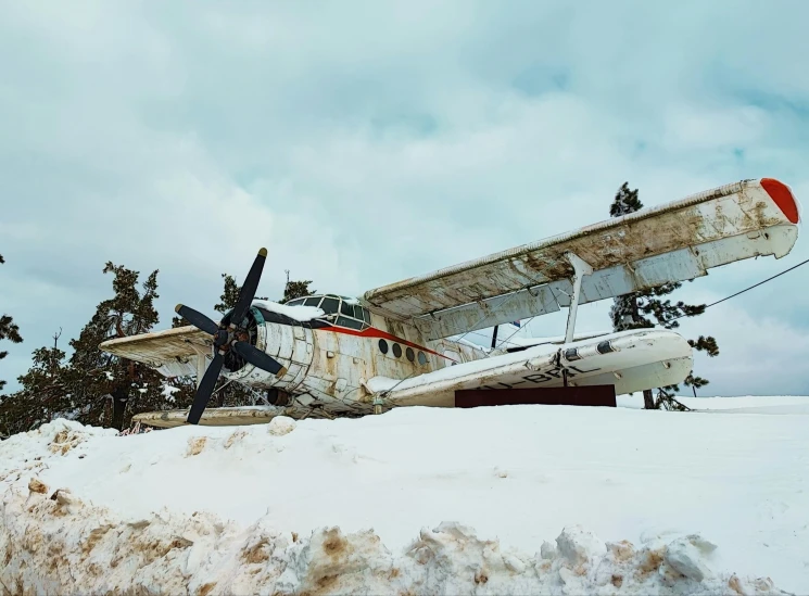 a small airplane sitting on top of a snow covered field, a colorized photo, pexels contest winner, hurufiyya, preserved historical, snow on the body, low angle, kalevala