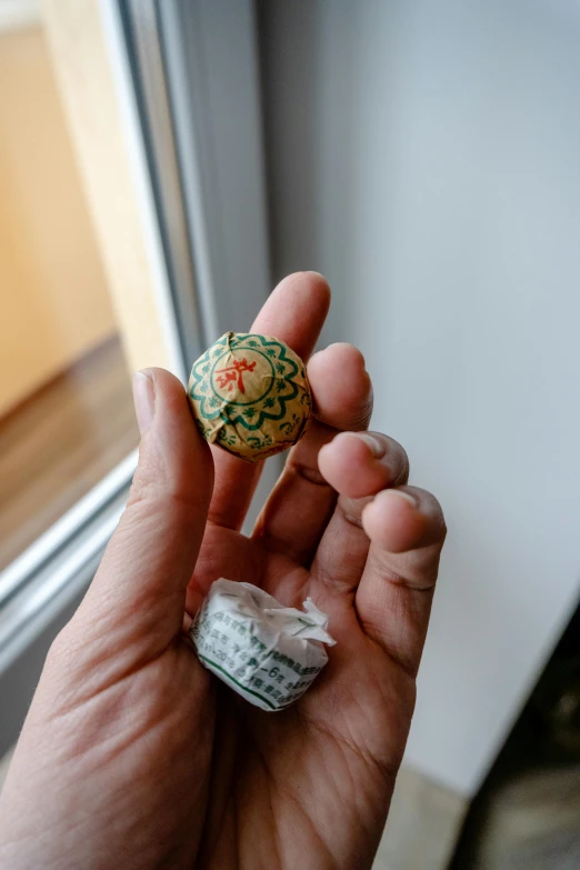 a close up of a person holding a small object, inspired by Ödön Márffy, next to window, healing pods, colombian, hotel room