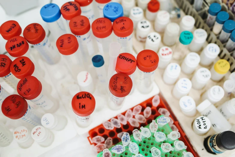 a bunch of bottles sitting on top of a counter, by Jessie Algie, unsplash, pathology sample test tubes, white and red color scheme, medical labels, many cryogenic pods