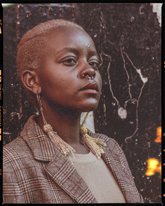 a close up of a person wearing a jacket, an album cover, inspired by Afewerk Tekle, trending on unsplash, afrofuturism, girl with short white hair, muted brown yellow and blacks, huge earrings and queer make up, instagram story