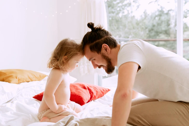 a man and a little girl sitting on a bed, pexels contest winner, dad bod, smiling at each other, avatar image, toddler