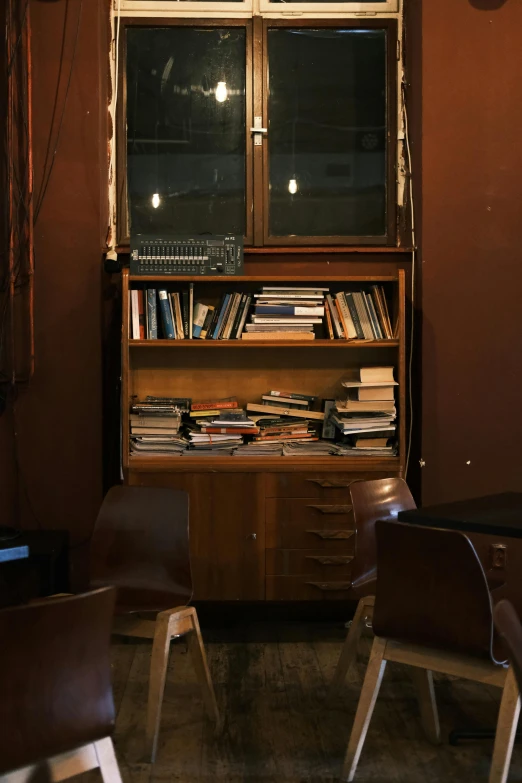 a couple of chairs sitting in front of a window, by Else Alfelt, unsplash, modernism, book case, inside a bar, old scientific documents, at nighttime