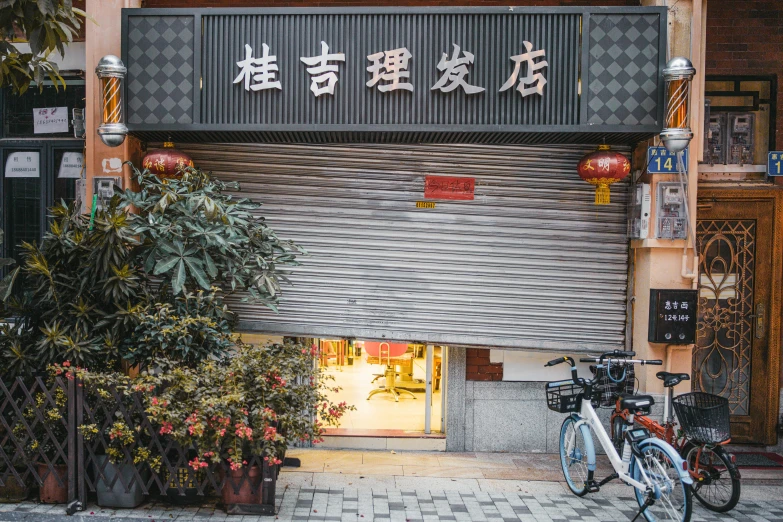 a couple of bikes parked in front of a building, by Daniel Lieske, mingei, shop front, chinese text, an escape room in a small, an ancient