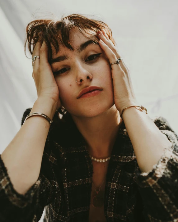 a woman sitting at a table with her hands on her head, inspired by Elsa Bleda, trending on pexels, mannerism, portrait of max caulfield, lily collins, photo of a hand jewellery model, 'i'm so tired