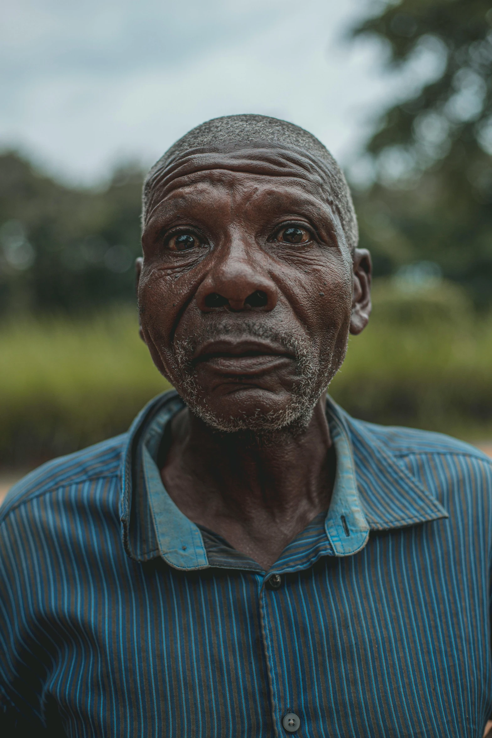 a man in a blue shirt holding a banana, by Will Ellis, pexels contest winner, wrinkly forehead, african man, portrait of forest gog, in the center of the image