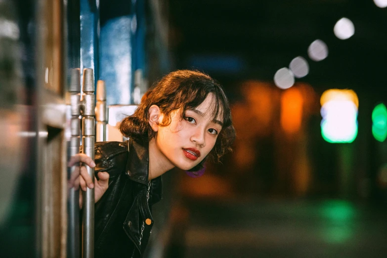 a close up of a person leaning on a pole, inspired by Yuko Tatsushima, trending on pexels, realism, kiko mizuhara, curly bangs, hero pose colorful city lighting, ethnicity : japanese