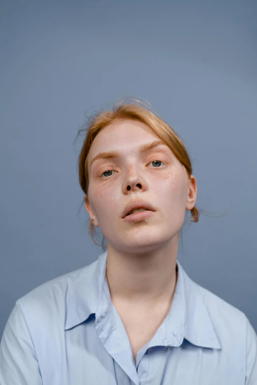 a close up of a person wearing a shirt, a character portrait, trending on pexels, pale bluish skin, studio portrait photo, a redheaded young woman, smooth symmetrical chin