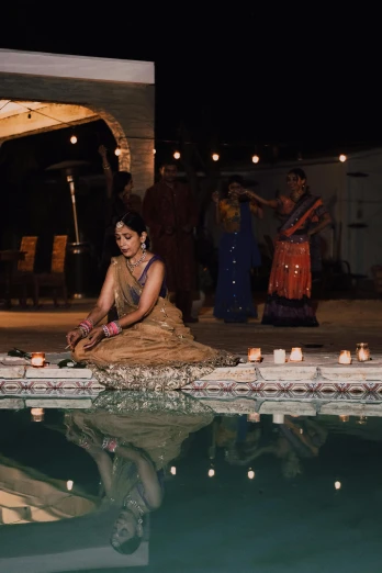 a woman sitting on the ground next to a pool, renaissance, lit with candles, bollywood, wedding, 2019 trending photo