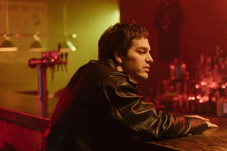 a man in a leather jacket sitting at a bar, an album cover, inspired by Nan Goldin, pexels, post malone, high resolution movie still, joe keery, pete davidson