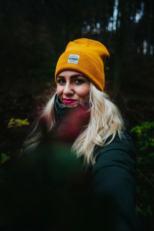 a woman taking a selfie in the woods, inspired by Louisa Matthíasdóttir, pexels contest winner, wearing a beanie, yellow, avatar image, sigma 85/1.2 portrait