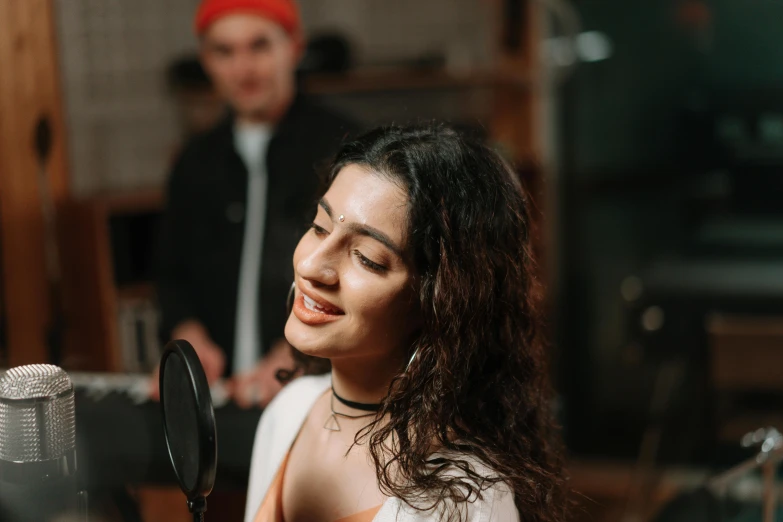 a woman singing into a microphone in a recording studio, an album cover, by Julia Pishtar, trending on pexels, hurufiyya, indian girl with brown skin, thumbnail, handsome girl, lorde