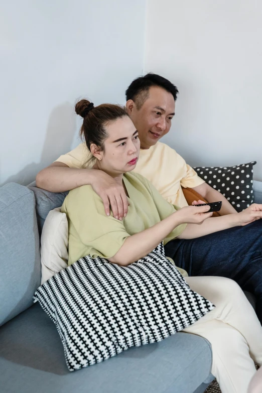 a man and a woman sitting on a couch, inspired by Zhang Xiaogang, pexels, square, watching tv, heartbroken, asian women