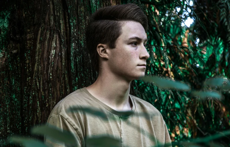 a young man standing in front of a tree, pexels contest winner, realism, androgynous face, flume, connor hibbs, thick jungle