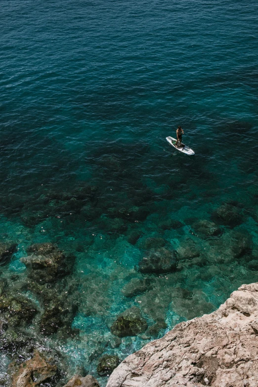 a person riding a surfboard on top of a body of water, reefs, dubrovnik, in the ocean, up close