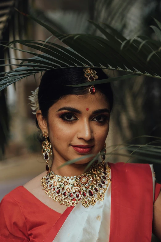 a woman wearing a red and white sari, wearing gold detailed choker, promo image, square, post graduate