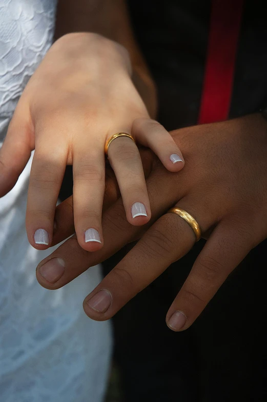 a close up of a person holding a wedding ring, mix of ethnicities and genders, wearing presidential band, gradient white to gold, couple