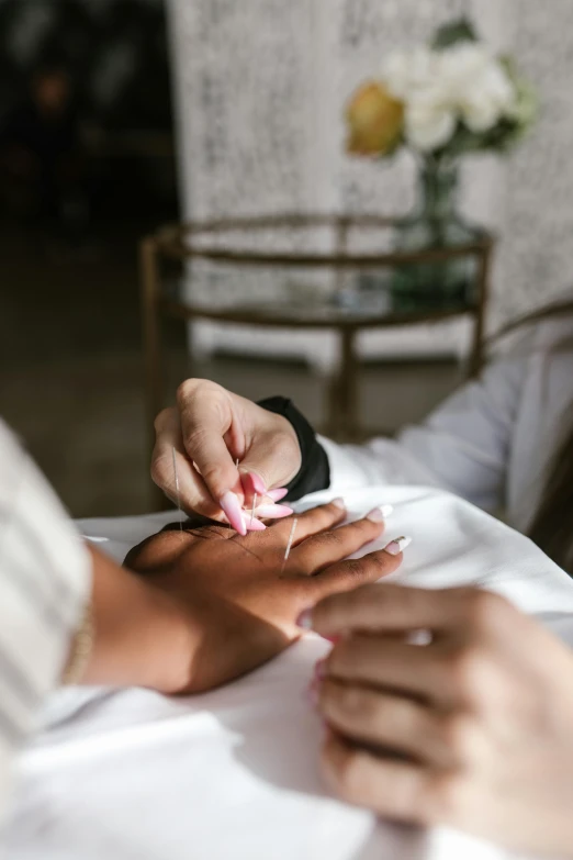 a woman getting her nails done in a salon, a photorealistic painting, by Olivia Peguero, trending on unsplash, long petals, acupuncture treatment, thumbnail, blurry