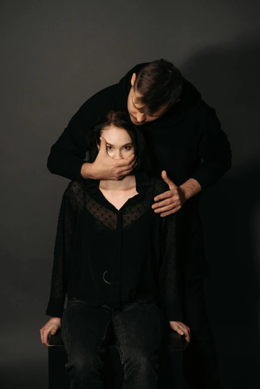 a man standing next to a woman in a black dress, by Adam Marczyński, trending on pexels, renaissance, touching heads, restrained, wearing a dark sweater, sitting down