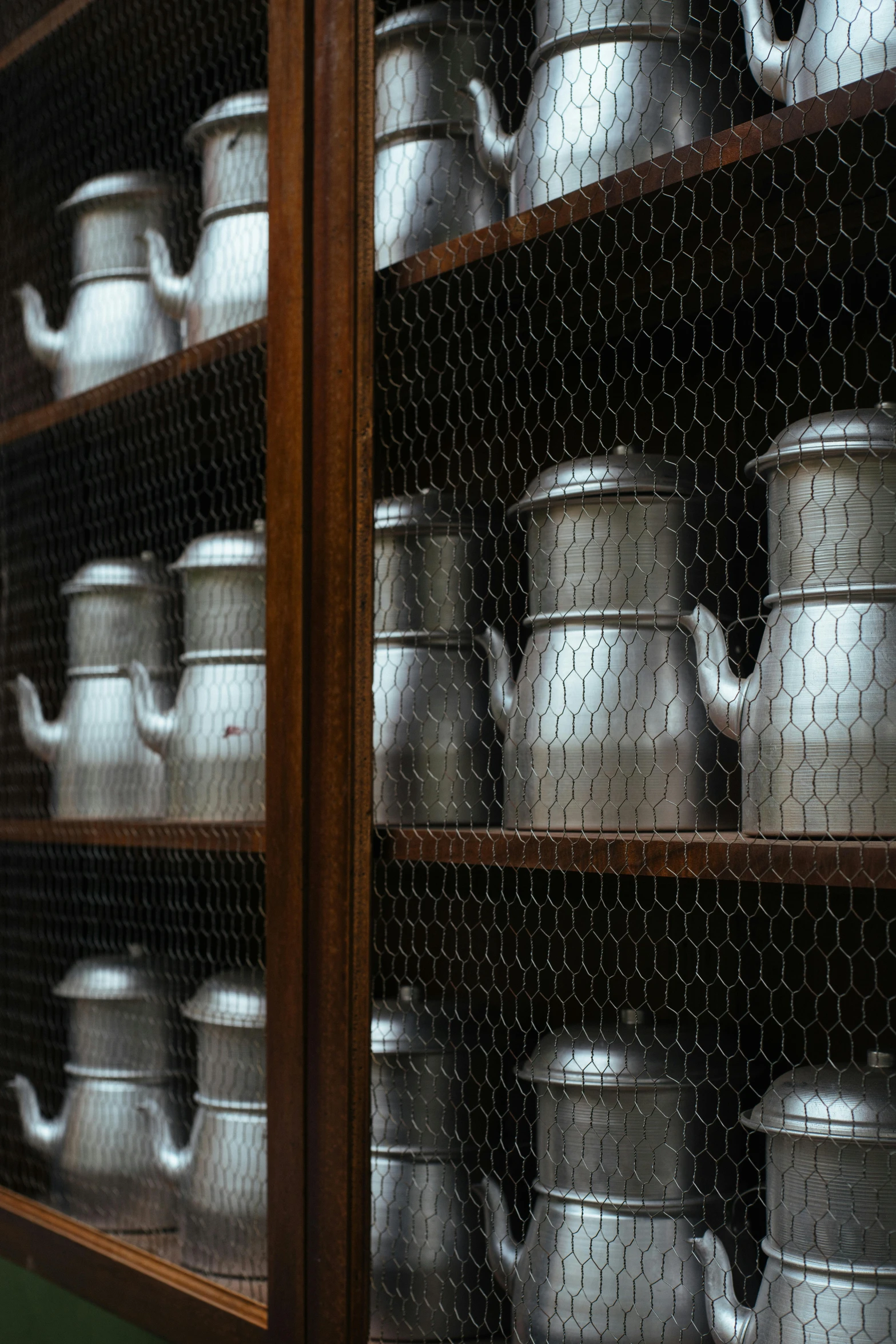 a shelf filled with lots of silver tea pots, by Frederik Vermehren, trending on unsplash, mesh wire, wooden cabinet, 8l, the british museum