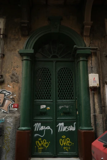 a green door sitting on the side of a building, an album cover, by Masolino, graffiti, neoclassic, gustav moreau, to me, merchants
