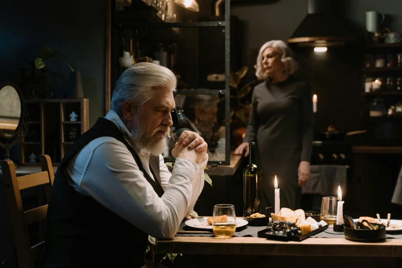 a man sitting at a table with a glass of wine, by Emma Andijewska, pexels contest winner, fantastic realism, silver hair and beard, dramatic movie still, family dinner, [ theatrical ]