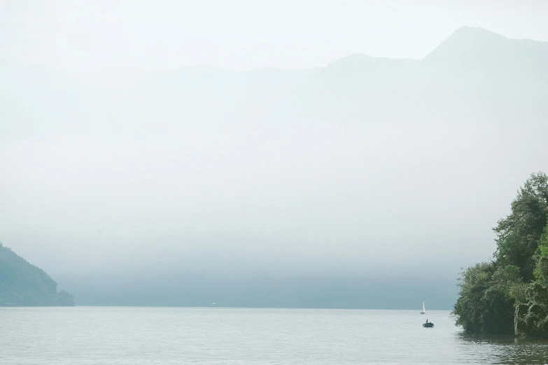 a couple of boats floating on top of a lake, inspired by Pierre Pellegrini, pexels contest winner, minimalism, light grey mist, loch ness monster, view from the sea, whistler