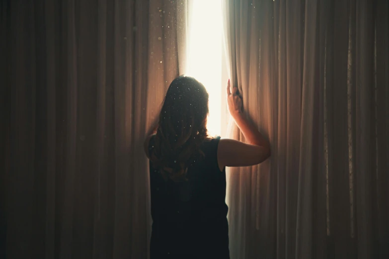 a woman standing in front of a window opening curtains, inspired by Elsa Bleda, pexels contest winner, magical realism, sparkling light, broken down, instagram post, reuniting