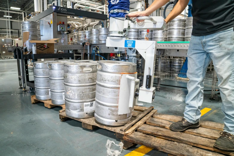 a man standing next to a stack of kegs, shutterstock, industrial robots, filling the frame, avatar image, full pallet image