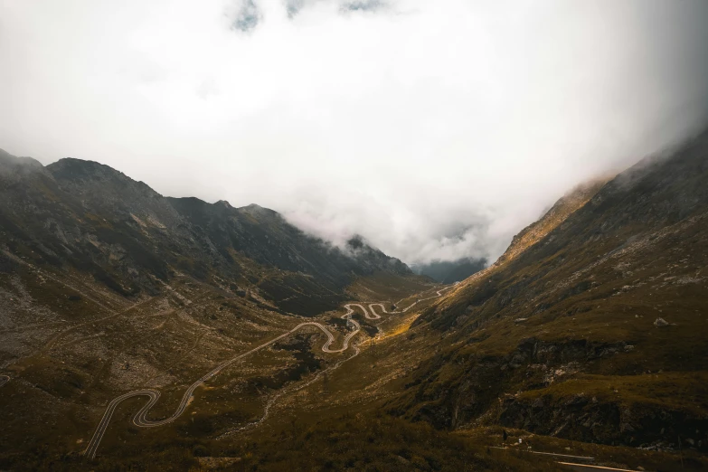 a winding road in the mountains on a cloudy day, an album cover, pexels contest winner, hurufiyya, overview, festivals, thumbnail, multiple stories