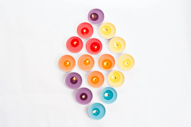 a group of colorful candles sitting on top of a white table, product shot, high quality product image”, light from top right, multicoloured