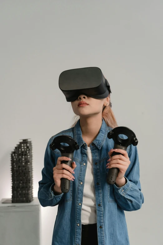 a woman in a denim shirt holding a pair of hair dryers, a hologram, by Adam Marczyński, trending on pexels, hypermodernism, futuristic vr headset, wearing a dark shirt and jeans, gamedev, asian female