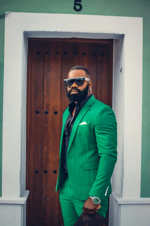 a man in a green suit standing in front of a door, an album cover, inspired by Charles Alston, trending on unsplash, happening, thick black beard, puerto rico, square, shades