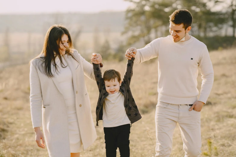 a family walking through a field holding hands, a picture, pexels, handsome, avatar image, husband wife and son, wearing casual clothes