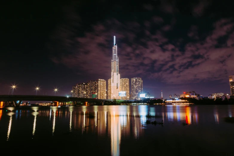 a large body of water with a city in the background, pexels contest winner, futuristic tower, during the night, vietnam, view from ground level