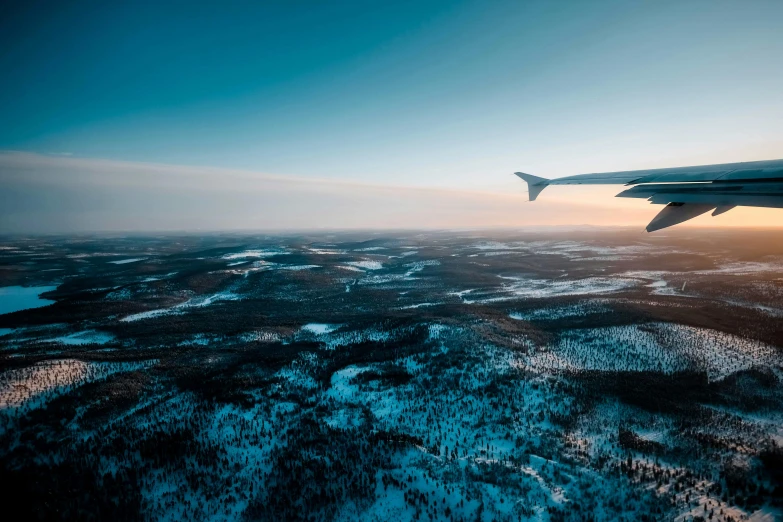 an airplane wing flying over a snowy landscape, by Jesper Knudsen, pexels contest winner, hurufiyya, bright nordic forest, thumbnail, looking onto the horizon, early evening