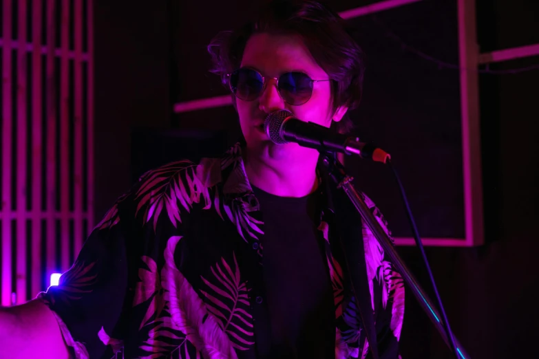 a man that is standing in front of a microphone, an album cover, by Byron Galvez, pexels, with sunglass, nightlife, dolman, student