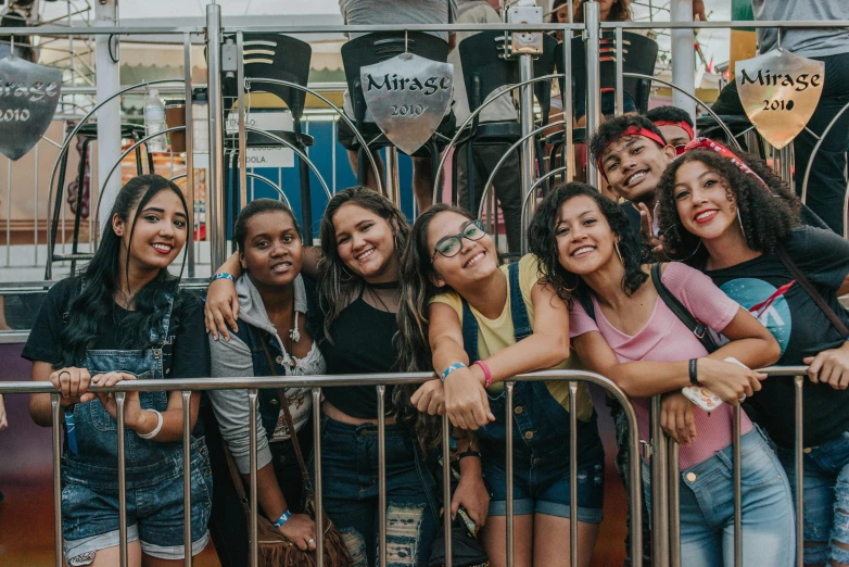 a group of women standing next to a metal fence, by Amelia Peláez, pexels contest winner, amusement park, latina skin, teenagers, at a mall