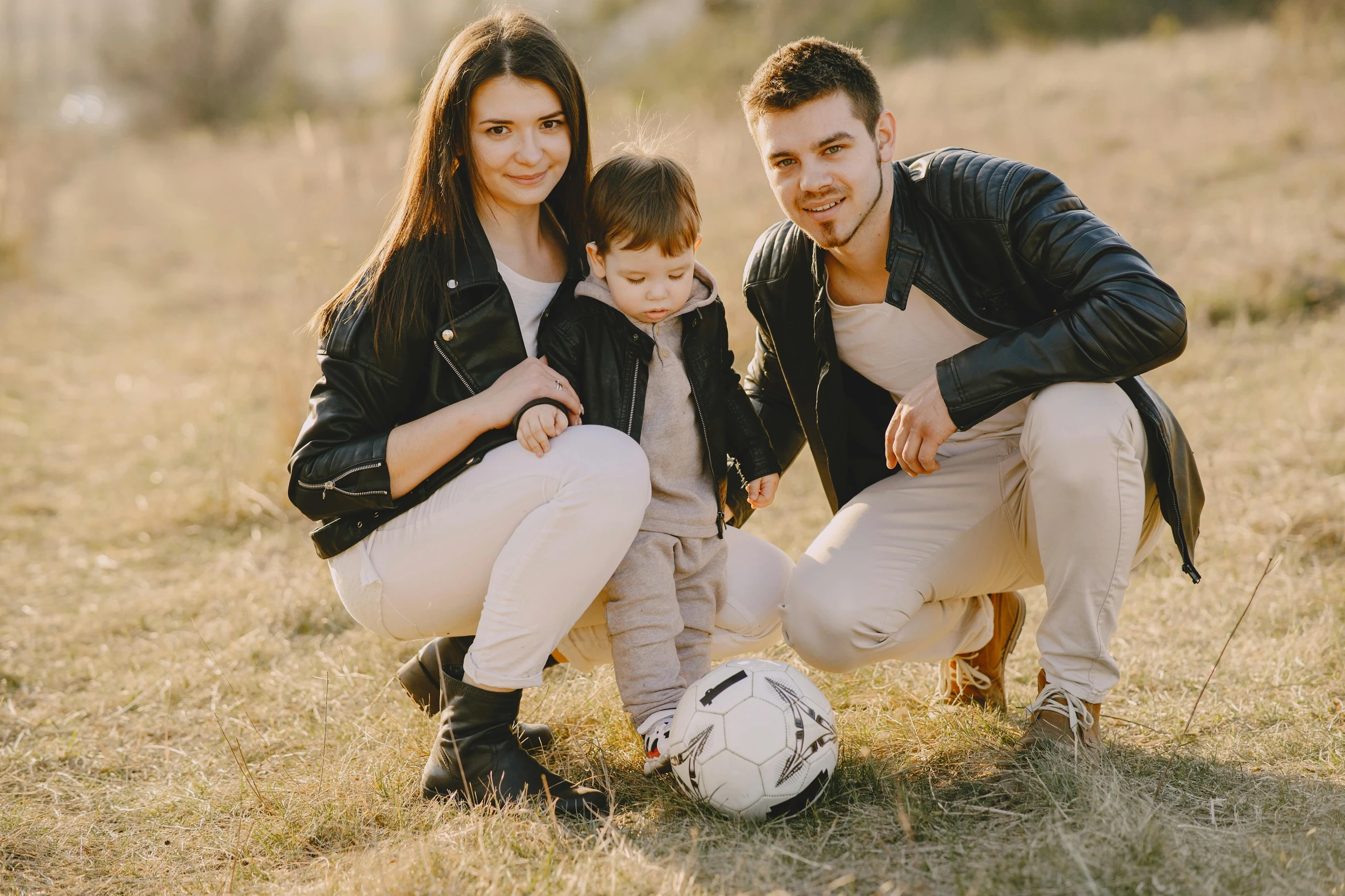 a man and woman kneeling next to a young boy with a soccer ball, a picture, by Alexander Fedosav, pexels contest winner, leather clothes, avatar image, husband wife and son, attractive photo